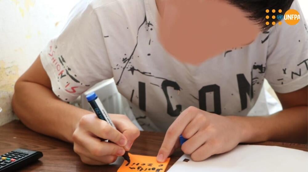 A young man in the Juvenile Re-education Institution in Kavaje while taking notes on a paper during a workshop