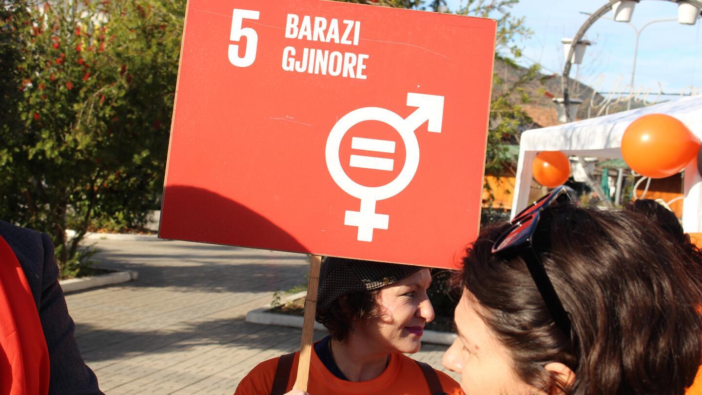 Elsona Agolli, a Program Analyst on Gender and Population Issues at UNFPA Albania, is wearing an orange t-shirt and holding a placard that reads: "Gender Equality"